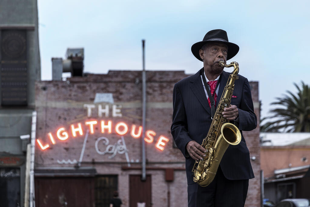 Charles Owens playing saxophone in front of the Lighthouse Cafe