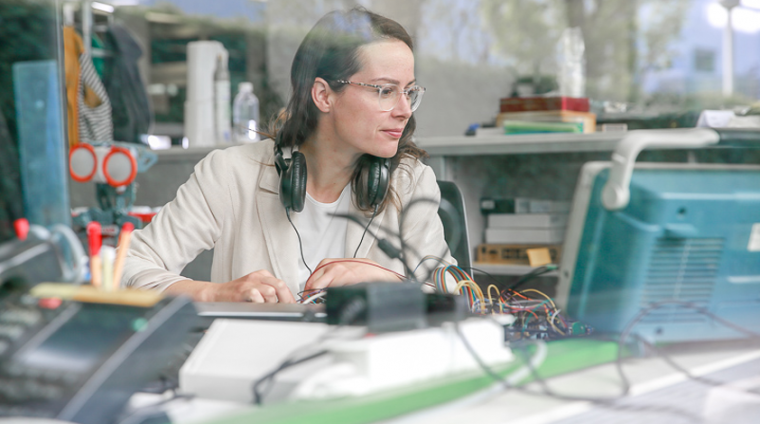 Anne bei der Arbeit: Der Bürotisch ist übersät mit Dutzenden, verschieden farbiger Kabel.