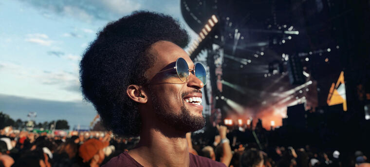 A man smiling using hearing protection at a music festival