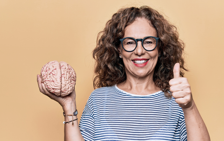 A woman holds a brain in one hand and gives a thumbs up with the other
